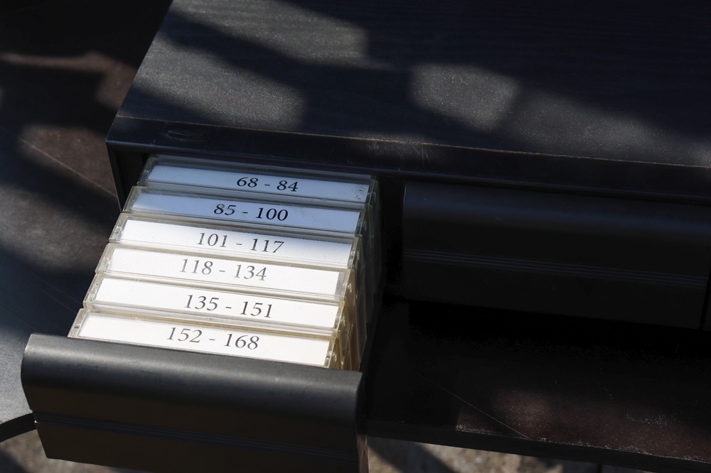 We zien lade met cassettebandjes met daarop allerlei cijfers geschreven. Het hoort bij het kunstwerk 'Open Call'.